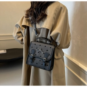 Detail of grey polka dot ballet style crossbody bag with silver bow on beige trench coat
