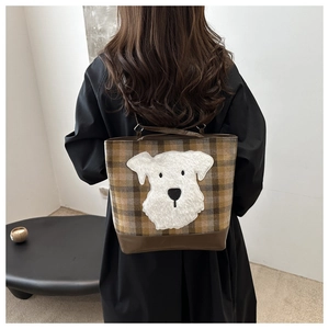 Dettaglio della borsa a quadri con toppa in peluche a forma di cane e base in pelle