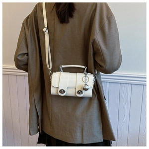 Rear view of model wearing a white crocodile pattern handbag with silver hardware