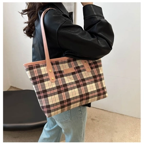 Detail of pink plaid tote bag with leather straps and gold rivets shown on a model