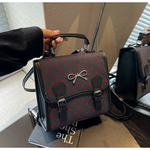 Close-up of retro gray canvas bag with red heart patterns and silver bow detail