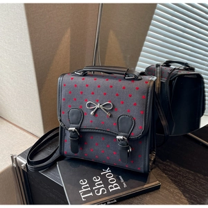 Detail of tweed crossbody bag featuring red heart embroidery and silver bow buckle