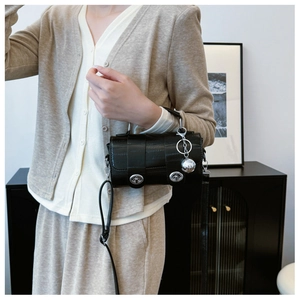 Detail of black crocodile texture cylindrical crossbody bag with silver twist locks