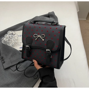 Close-up of retro backpack with red heart embroidery and silver metal bow buckle