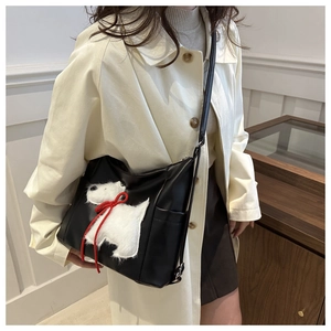 Detailansicht der schwarzen Kunstledertasche mit süßem weißem Plüsch-Hundeaufnäher