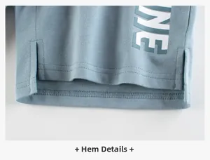 Détail d'un short en tricot bleu-gris pour enfant avec fente latérale et imprimé NE