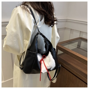 Close-up of black PU leather shoulder bag with white faux fur ears and a red bow detail