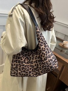 Leopard print canvas hobo shoulder bag with black strap on trench coat model