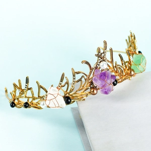 Corona de hada dorada con cristales crudos de colores y perlas sobre base de piedra