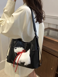 Chic black leather shoulder bag with a cute plush white puppy patch and red bow detail