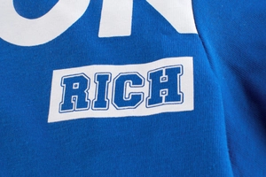 Vue macro du tissu en maille bleue avec lettrage blanc RICH et OK imprimé sur t-shirt