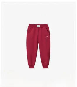Detail view of red kids sports pants featuring elastic waistband and small pink embroidery