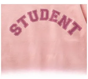 Close-up of pink cotton fabric featuring American varsity style high school letter print