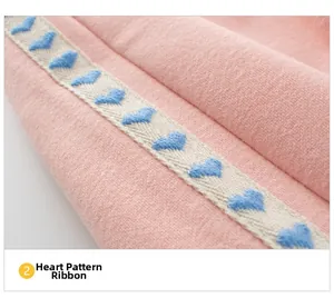 Detail of pink knitted fabric featuring a decorative ribbon with blue heart patterns