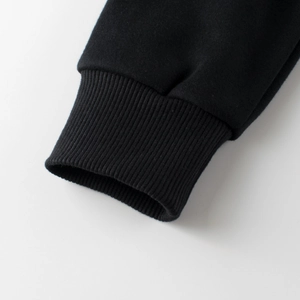 Dettaglio del polsino a coste elasticizzate su felpa in maglia nera foderata in pile per bimbi