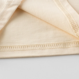Close-up of beige cotton knit girls long sleeve t-shirt hem with double-needle stitching