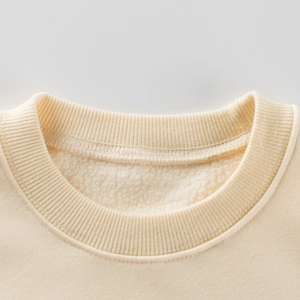 Kids cream sweatshirt with ribbed crewneck and warm fleece lining shown in close-up view