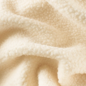 Close-up of soft beige Sherpa fleece fabric texture for children's autumn sweatshirts