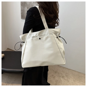Détail du grand sac cabas blanc avec cordons latéraux et texture en cuir premium