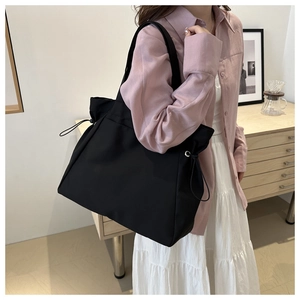 Détail du grand sac cabas noir avec cordon de serrage réglable et bandoulière en toile