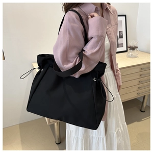Détail du grand sac cabas noir en nylon avec cordons de serrage latéraux et œillets