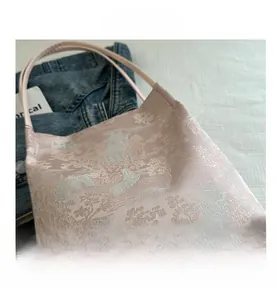 Detailed embroidery of Chinese pavilions on pink silk tote bag with fine stitching