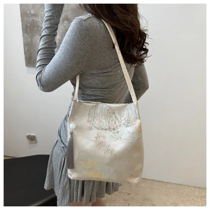Detail of floral embroidery and jade tassel on a Chinese style cream tote bag