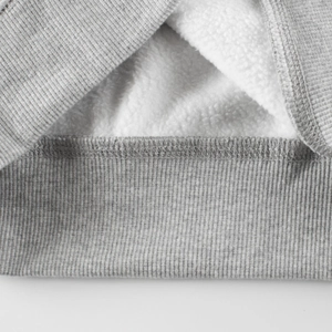 Detalle de sudadera gris para niños con forro polar cálido y acabados de punto elástico