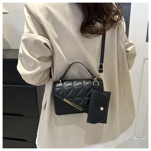 Detail of black quilted crossbody bag with small coin purse and golden hardware on model