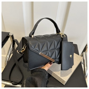 Detail of black quilted leather handbag with gold metal bar and detachable coin purse pouch
