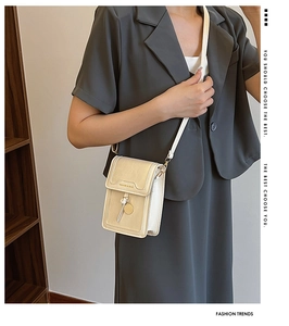 Close-up of cream mini phone bag with litchi texture and golden metal pendant detail