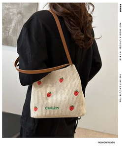 Detailed view of handmade straw shoulder bag with strawberry embroidery and leather strap