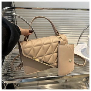Detail of beige quilted handbag with gold metal bar and detachable mini coin purse accessory