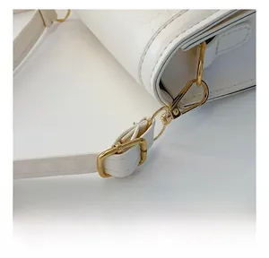 Detail shot of bright gold hardware hook and adjustable white leather shoulder strap