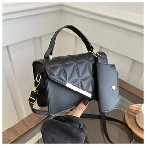 Close-up of black quilted handbag with golden buckle and matching small coin purse charm