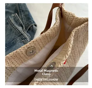 Detail of the magnetic snap closure on the large woven straw tote with leather handles