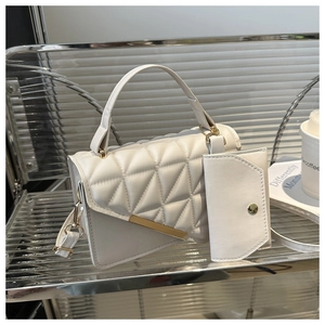 Detailed view of white quilted faux leather handbag with gold metal bar and coin purse