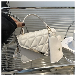 Detail of white quilted leather handbag with gold metal bar and matching mini pouch