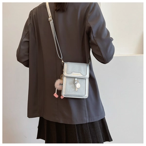 Silver metallic mini crossbody bag with pink plush charm and fashion text detail