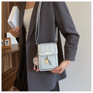 Detail of silver metallic mini crossbody bag with tassel and plush pink charm