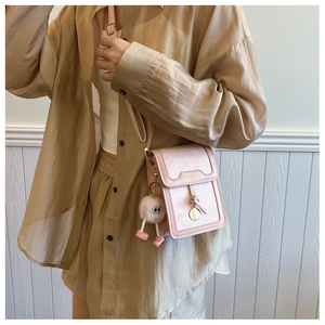 Pink mini crossbody bag featuring荔枝 pattern leather and cute fur monster pendant detail