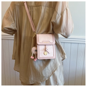 Close-up of pink mini crossbody phone bag with a cute plush charm on a model