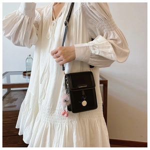 Mini black crossbody phone bag with gold lettering and cute pink furry pompom charm