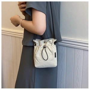 Detailansicht der cremefarbenen Canvas-Beuteltasche mit Kordelzug und schwarzem Riemen