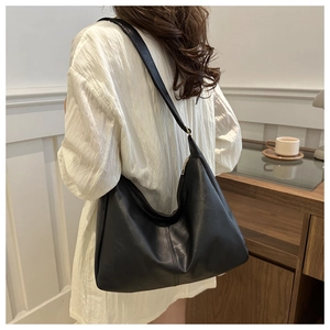 Detailed side view of a large black minimalist hobo shoulder bag on a female model