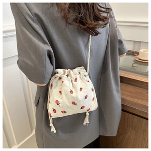 Détail de la texture velours côtelé fraise et cordon de serrage du mini sac seau
