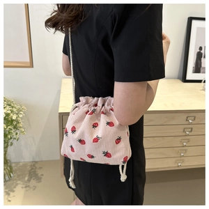Detail of pink corduroy bucket bag with red strawberry prints and white cotton drawstrings