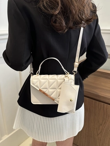 White quilted crossbody bag with gold metal trim and mini pouch shown in lifestyle setting