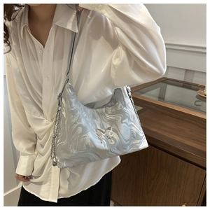 Detail of silver marble textured shoulder bag featuring a metallic butterfly buckle