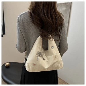 Detail of hobo shoulder bag featuring pearl heart charms and rhinestone bow decoration